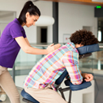 Therapist providing chair massage at workplace event to relieve tension and promote wellness at Spirit & Body Massage Prescott Valley